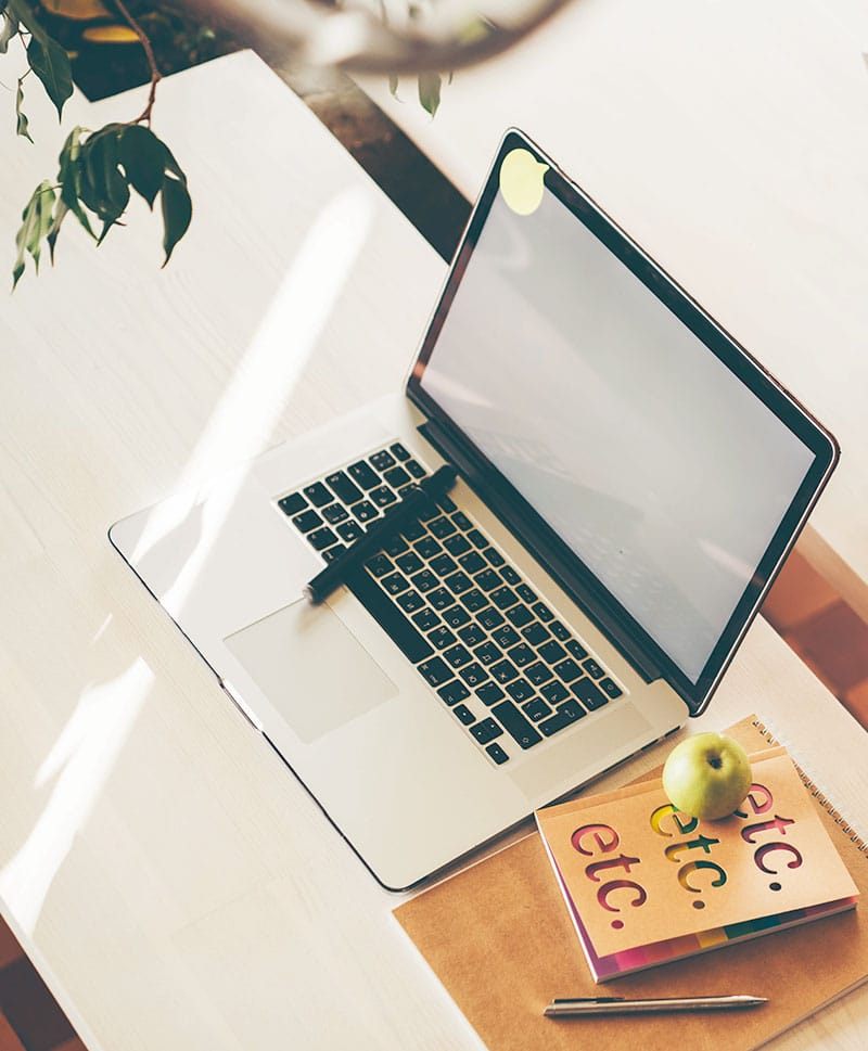 Laptop und Notizbuch auf einem hellen Schreibtisch
