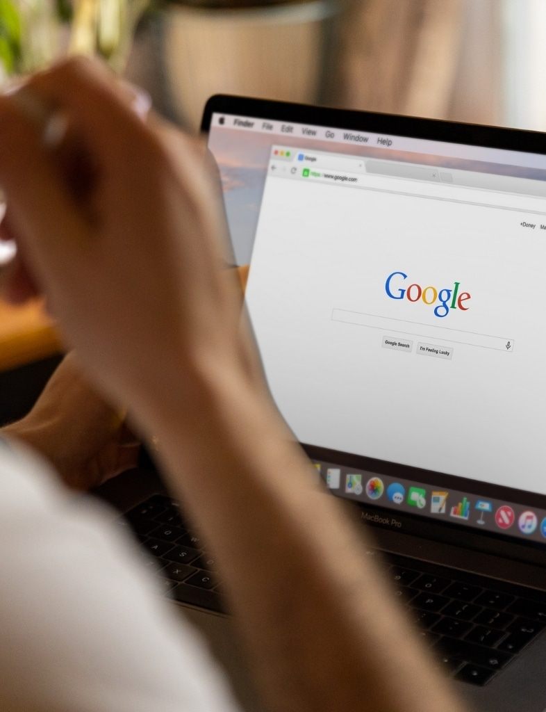 Hand am Laptop mit der Google-Suche auf dem Bildschirm